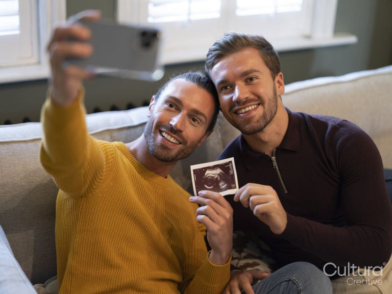 Pride couple taking selfie with ultrasound scan at home