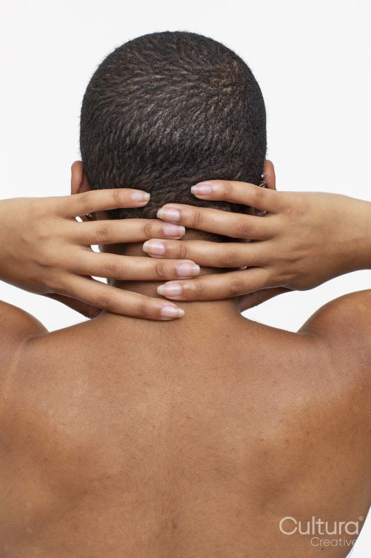 Rear view of shirtless woman with hands behind head