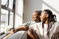 Portrait of happy couple looking through window at home