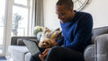 Man using tablet, dog resting on his lap
