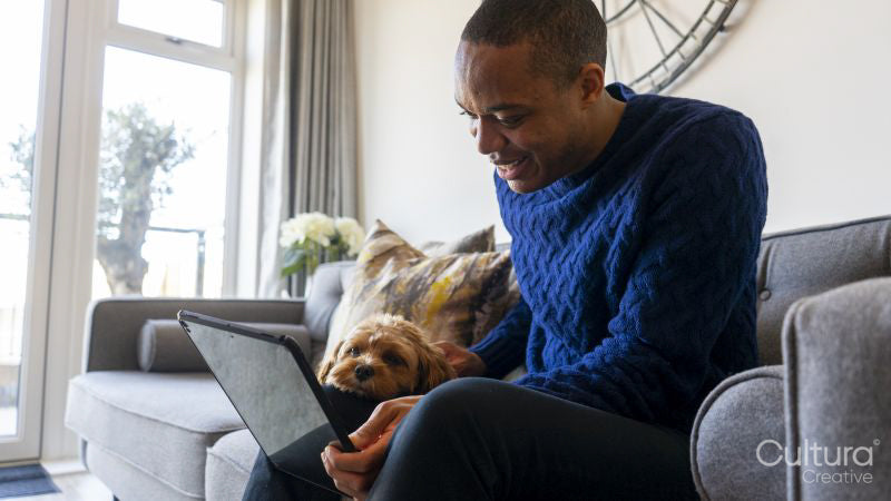 Man using tablet, dog resting on his lap