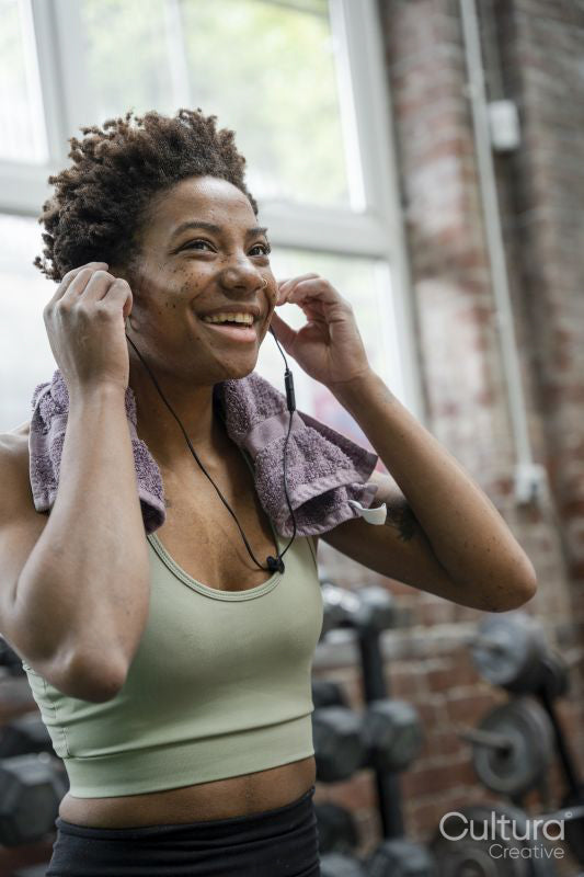 Woman putting earphones on during training on gym