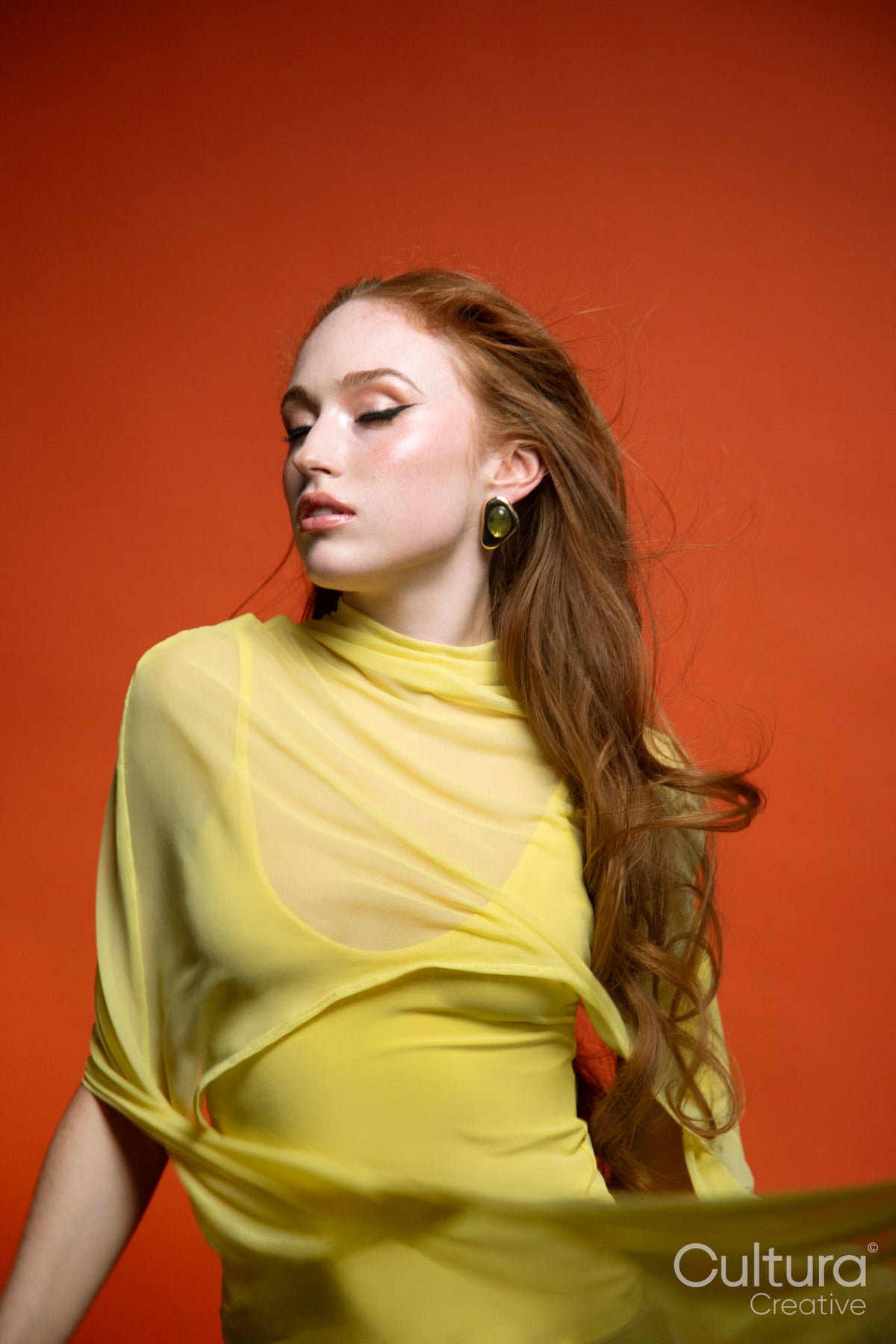 Woman in a yellow dress with windswept hair in a studio