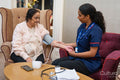 Nurse taking blood pressure of senior woman at nursing home