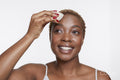 Studio portrait of smiling woman applying make up foundation with sponge