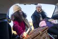 Female friends grabbing bags from car trunk