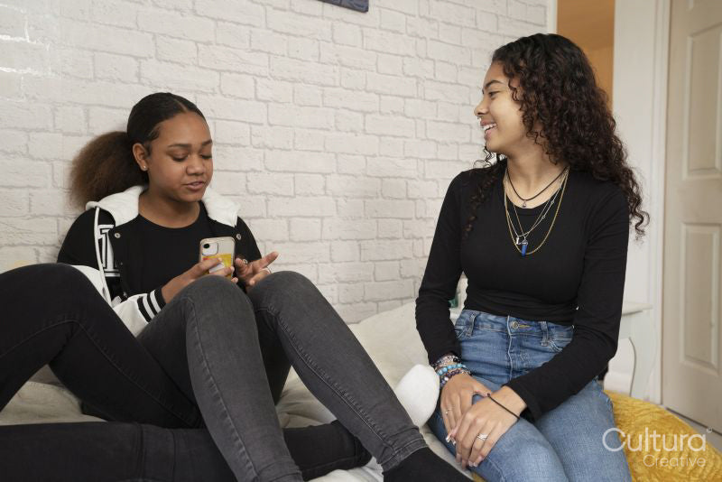Teenage girls talking and relaxing on bed at home