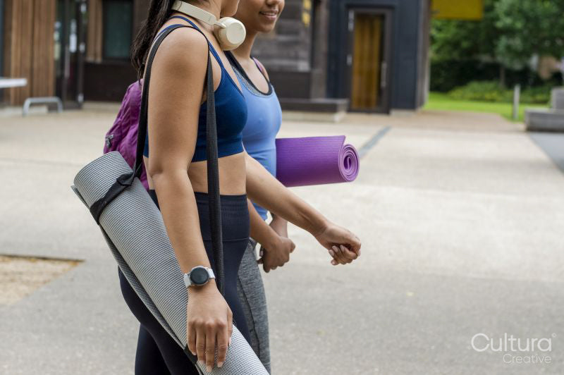 Female friends walking with yoga mats