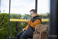 Man sitting on bench at bus stop, using smart phone