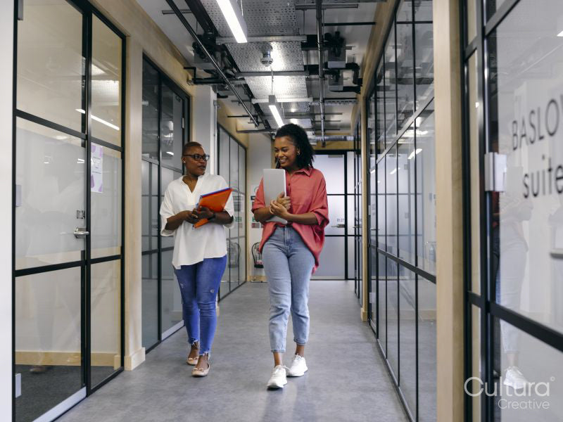 Two women walking in office hallway