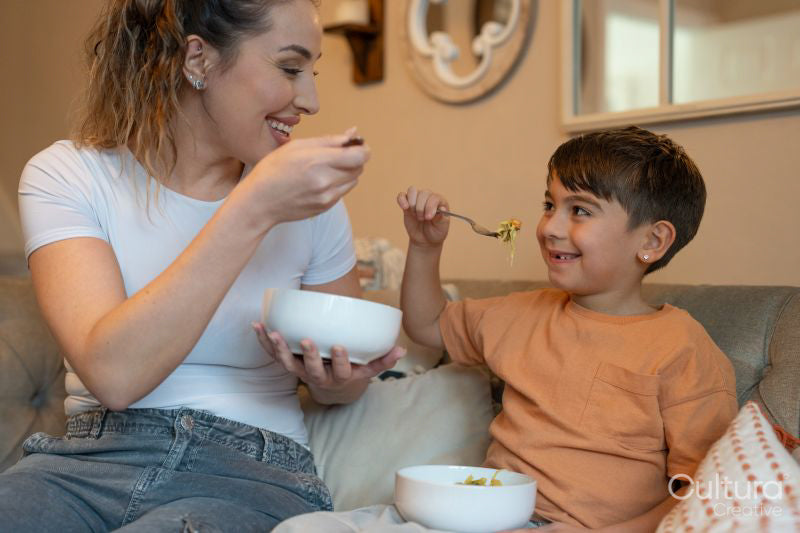 Mother and son sitting on sofa and eating lunch