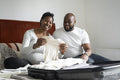 Pregnant woman and man holding baby clothing on bed