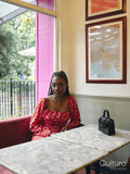 Portrait of woman in red dress sitting at cafe table