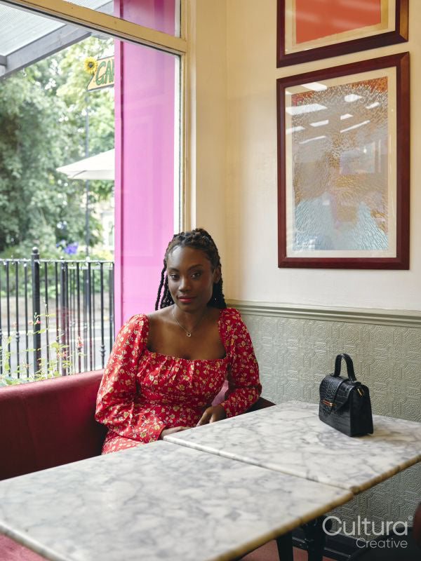 Portrait of woman in red dress sitting at cafe table