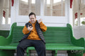 Man sitting on bench and waving to smart phone