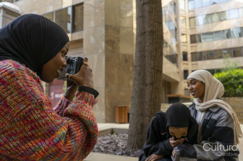 Young woman photographing friends wearing hijabs in city