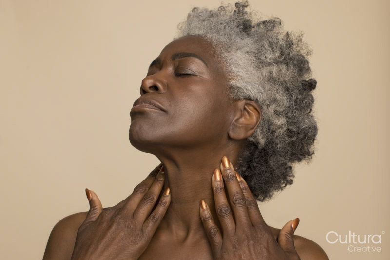 Studio shot of mature woman with eyes closed touching neck