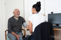 Female doctor taking senior patients blood pressure in office