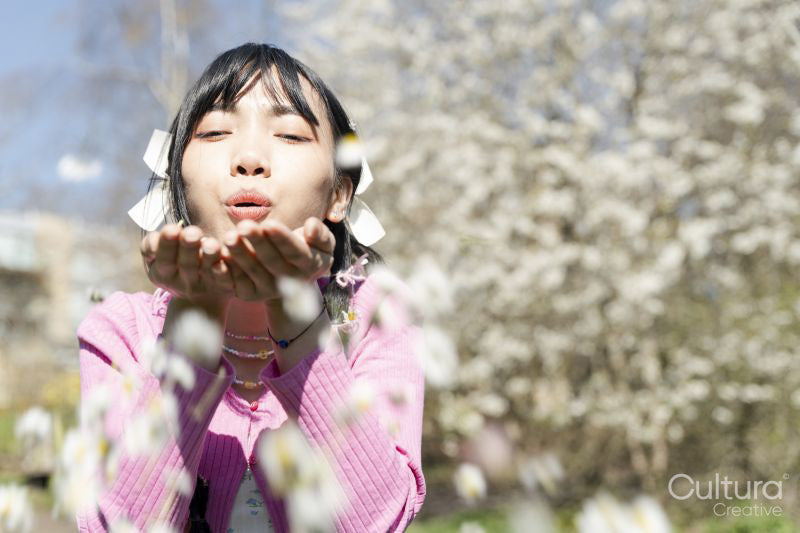 Portrait of young woman blowing flowers
