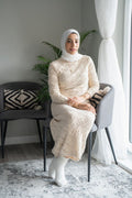 Portrait of smiling woman in hijab sitting in chair at home