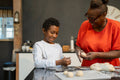 Boy with grandmother preparing dough in kitchen
