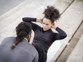 Man assisting woman doing sit-ups outdoors