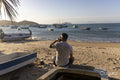 Rear view of man sitting at beach talking on phone