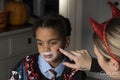 Close-up of woman applying red paint on son''s face for Halloween