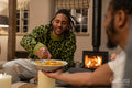 Smiling friends relaxing at home, sharing tortilla chips
