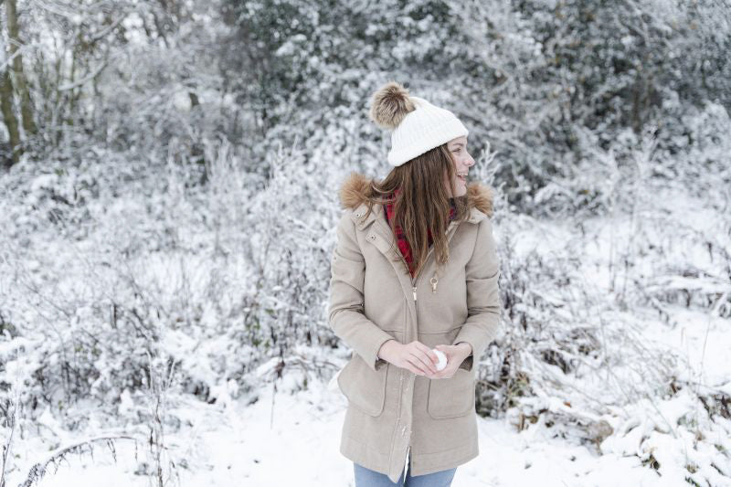 Smiling woman holding snow ball in winter landscape