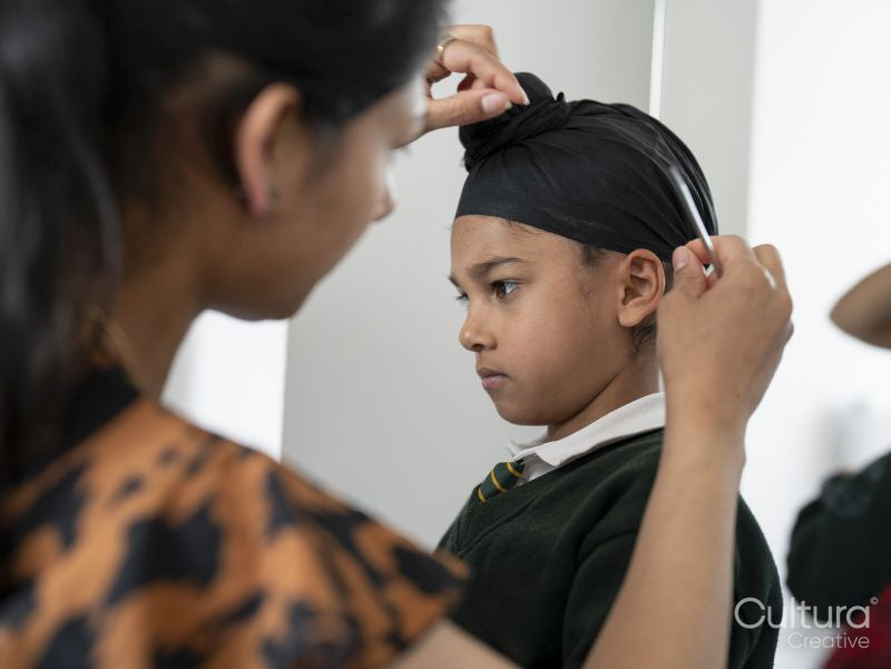 Mother wrapping traditional turban on son's head