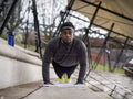 Athletic man doing push-ups on steps outdoors