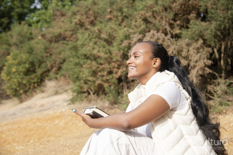 Portrait of smiling woman with book sitting on beach