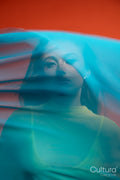 Woman in a yellow dress veiled by flowing blue fabric