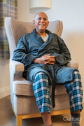 Senior man sitting in armchair with hearing aid in his room at nursing home