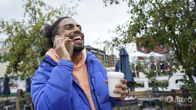 Young man holding coffee and talking on phone