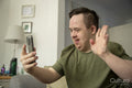 Man sitting on sofa and waving to smart phone