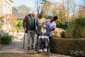 Senior people accompanied by nurse going on walk in park