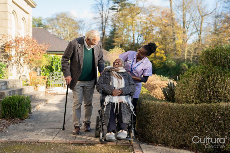 Senior people accompanied by nurse going on walk in park