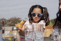 Girl pouring orange juice into drinking glass in outdoor restaurant