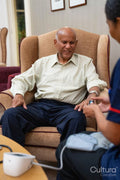 Nursing assistant using pulse oximeter on senior man at nursing home