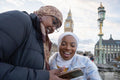 Young female tourists in hijabs using phone on Westminster Bridge