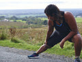 Female runner stretching on roadside
