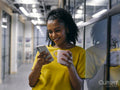 Woman drinking coffee and using phone in office hallway