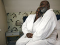 Mature couple in bathrobes sitting on bed in hotel room