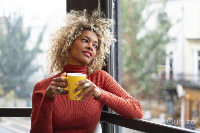 Woman holding mug and looking through window
