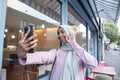 Young woman in hijab taking selfie in front of cafe