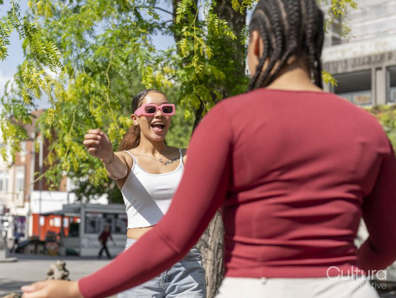 Two female friends greeting in city street