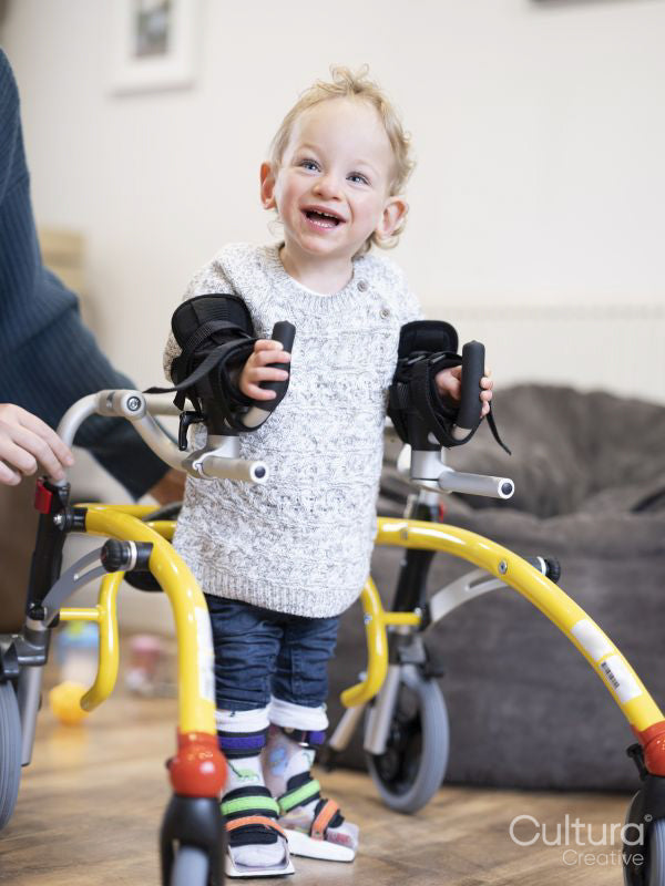 Boy with cerebral palsy using mobility walker and leg braces