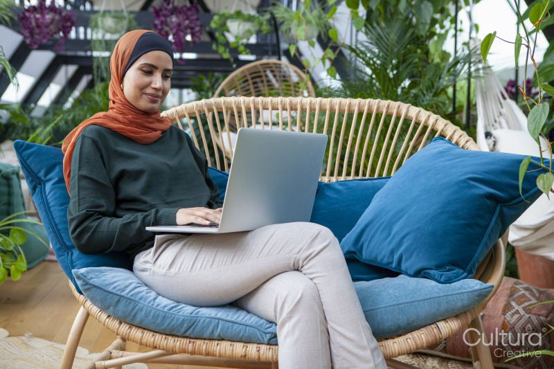 Woman wearing headscarf using laptop at home